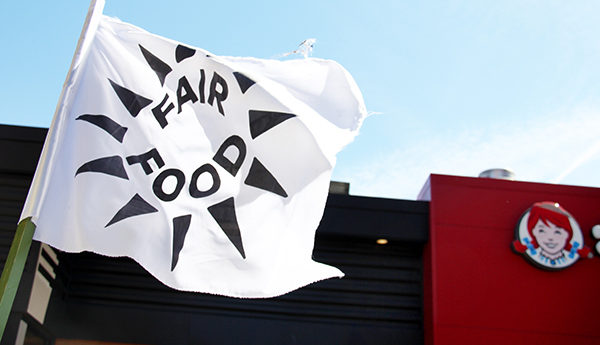 White flag with "Fair Food" logo flying in front of a Wendy's fast food restaurant