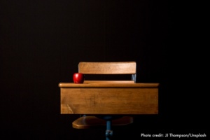 Desk and chair with red apple on the desk.