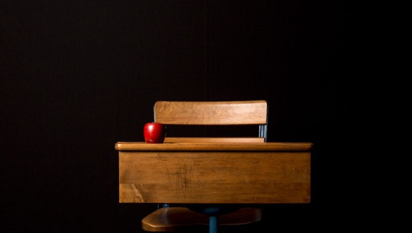 Desk and chair with red apple on the desk.