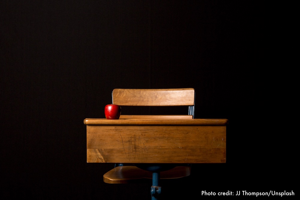 Desk and chair with red apple on the desk.