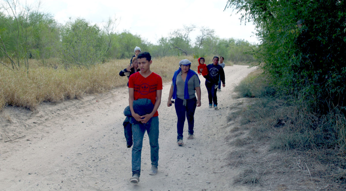 McAllen, Texas, USA - September 21, 2016: A group of Central Americans walks down a road prior to being picked up by the Border Patrol for illegally crossing the Rio Grande River into the U.S. in deep south Texas. There has been a flood of mothers with children and unaccompanied minors from Central America fleeing gang violence crossing illegally over the past several months.