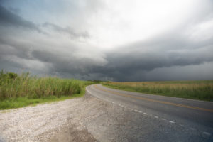 A desolate road in southern Louisiana; a storm cloud in the background.