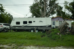 A trailer sitting in front of a damaged home.