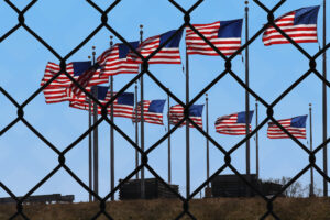 Several American flags seen through a chainlink fence