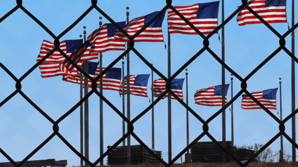 Several American flags seen through a chainlink fence