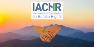 Logo of Inter-American Commission on Human Rights with an image of holding hands and mountain sunset background