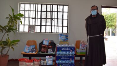 An Albergue staff member standing next to food supplies