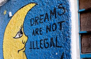 A picture containing text, building, blue Description automatically generatedA mural of a crescent moon that states “Dreams are Not Illegal”. (Casa Tochan)