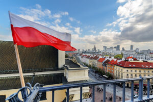 Poland Flag in Blue Sky and Warsaw in background