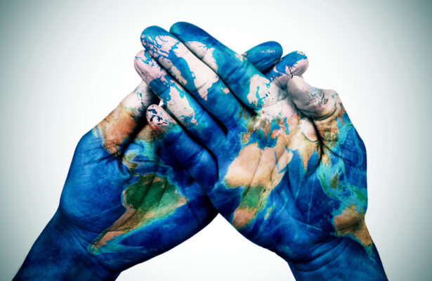 A pair of hands with the globe painted over them
